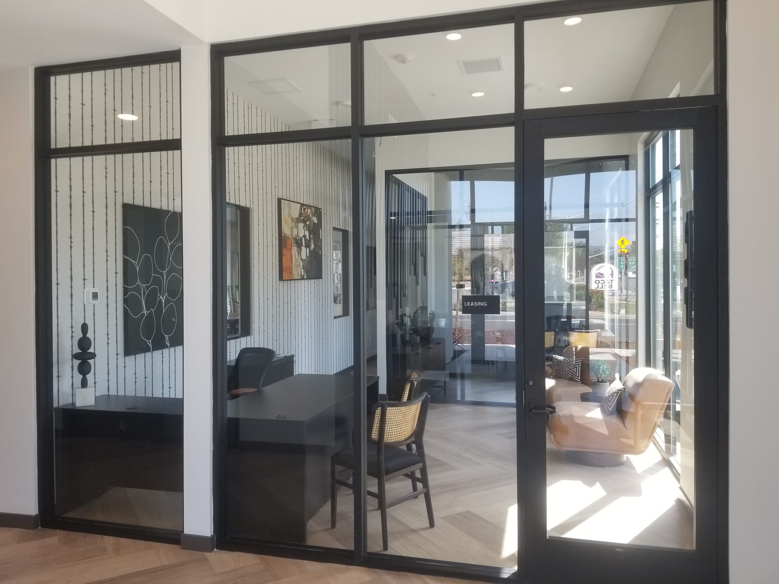 Interior office glazing with black aluminum frames, transom panels, and full-glass door