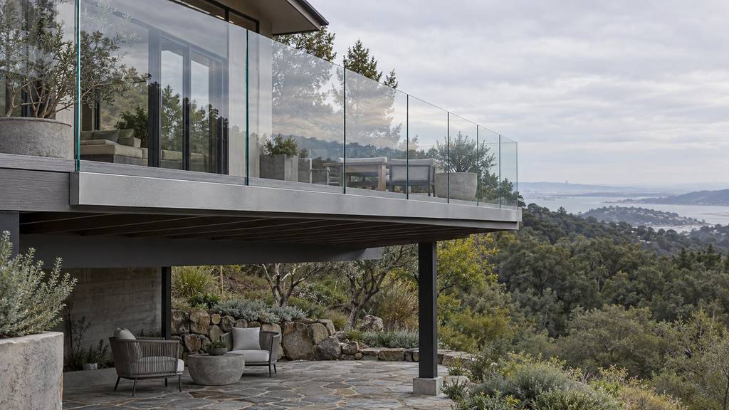 Frameless glass railing fascia-mounted on an elevated deck above a stone patio in the Bay Area